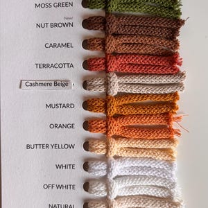 May include: A color swatch card featuring fourteen braided cord samples in various shades including Midnight Dust, Ink Blue, Moss Green, Nut Brown, Caramel, Terracotta, Cashmere Beige, Mustard, Orange, Butter Yellow, White, Off White, Natural, Golden Natural, and Nude.