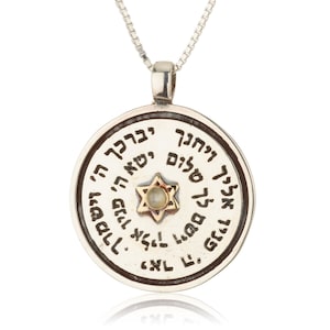 May include: Silver pendant necklace with a round charm featuring a Star of David with a white stone in the center. The charm is inscribed with Hebrew text.