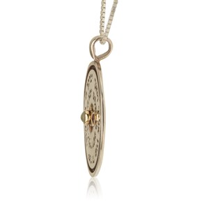 May include: Silver pendant necklace with a round charm featuring a Star of David and Hebrew text. The charm has a gold accent in the center.