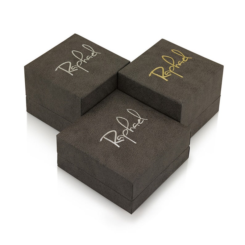 Puede incluir: Tres cajas cuadradas grises con la palabra "Raphael" en relieve en cada caja en diferentes colores: dorado, plateado y blanco.