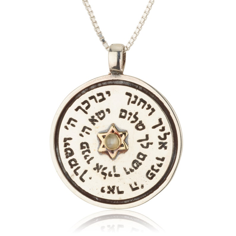 May include: Silver pendant necklace with a round charm featuring a Star of David with a white stone in the center. The charm is inscribed with Hebrew text.