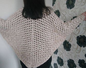 May include: A light pink crocheted cardigan with a loose, open-weave design. The cardigan has long sleeves and a slightly cropped length.