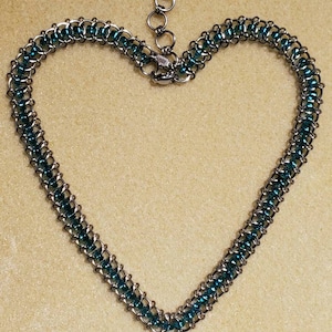 May include: A silver chain necklace with teal blue beads. The necklace is in the shape of a heart.