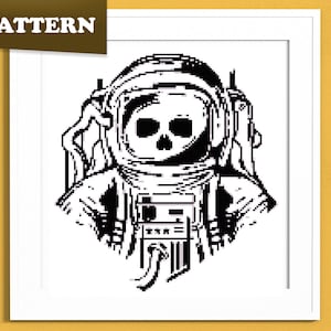 Puede incluir: Patrón de punto de cruz en blanco y negro de un astronauta con una cara de calavera dentro del casco. El astronauta lleva un traje espacial. La palabra "PATTERN" está en la esquina superior izquierda.