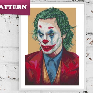Puede incluir: Un patrón de punto de cruz del Joker de la película "Joker" con cabello verde, labios rojos y un traje rojo y azul.