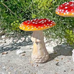 May include: A red and white mushroom garden statue with white spots. The mushroom has a white stem with a textured surface.