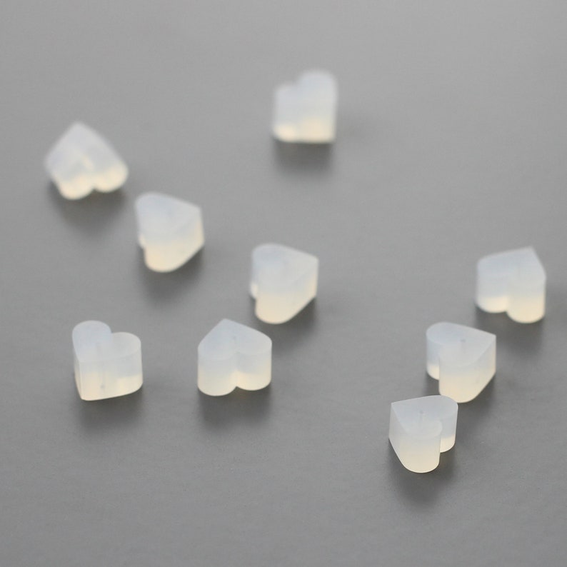 May include: Ten small, translucent white heart-shaped charms. The charms are made of a smooth, rubbery material.