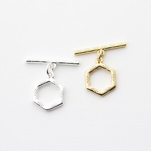 Peut inclure: Deux fermoirs à glissière argentés et dorés avec un motif hexagonal. Les fermoirs sont en métal et ont une finition polie.