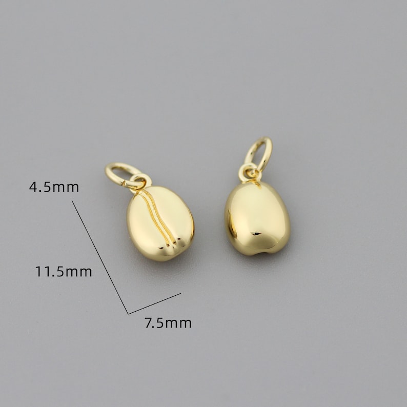 K&ouml;nnte beinhalten: Zwei goldfarbene Kaffebohnen-Anh&auml;nger, jeder misst 11,5 mm x 7,5 mm. Die Anh&auml;nger sind 4,5 mm dick.