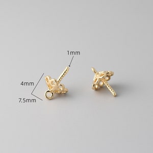 May include: Two gold-toned metal bead caps with a decorative filigree design. The caps are 7.5 mm wide, 4 mm tall, and have a 1 mm diameter hole.