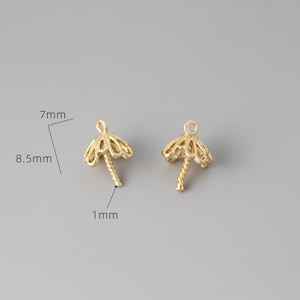 May include: Two gold-toned metal bead caps with a decorative, scalloped design. Each cap has a 1 mm long, twisted post for attaching beads. The caps measure 7 mm in diameter and 8.5 mm in height.