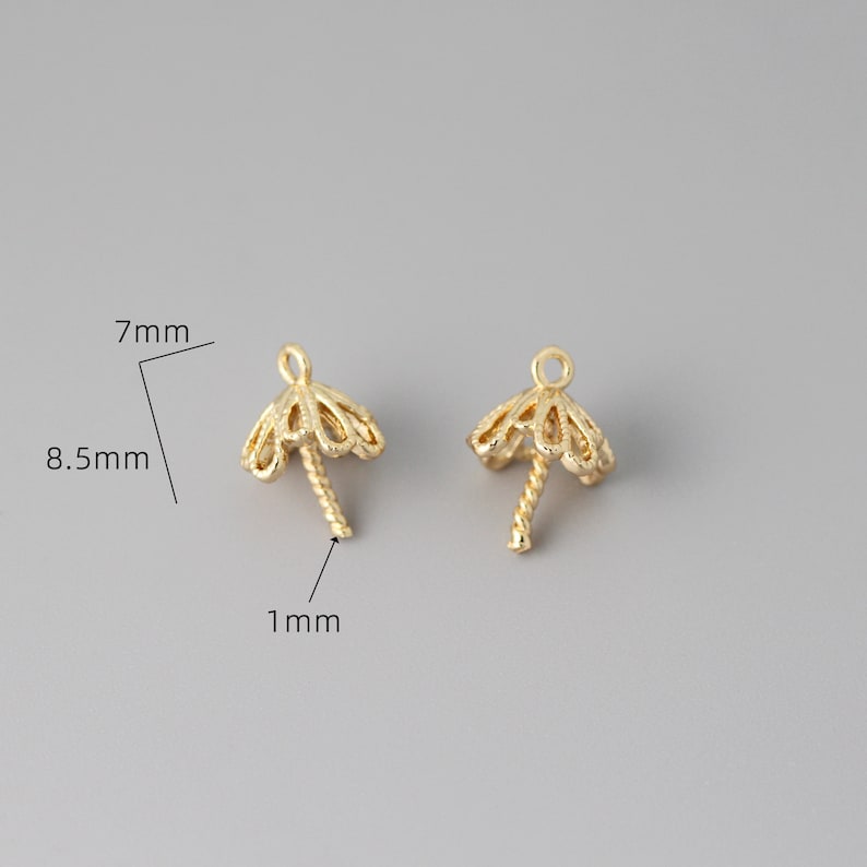 May include: Two gold-toned metal bead caps with a decorative, scalloped design. Each cap has a 1 mm long, twisted post for attaching beads. The caps measure 7 mm in diameter and 8.5 mm in height.