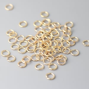 Puede incluir: Un montón de anillas de salto doradas, un tipo de hallazgo de joyería utilizado para conectar cadenas, cordones y otros componentes de joyería.