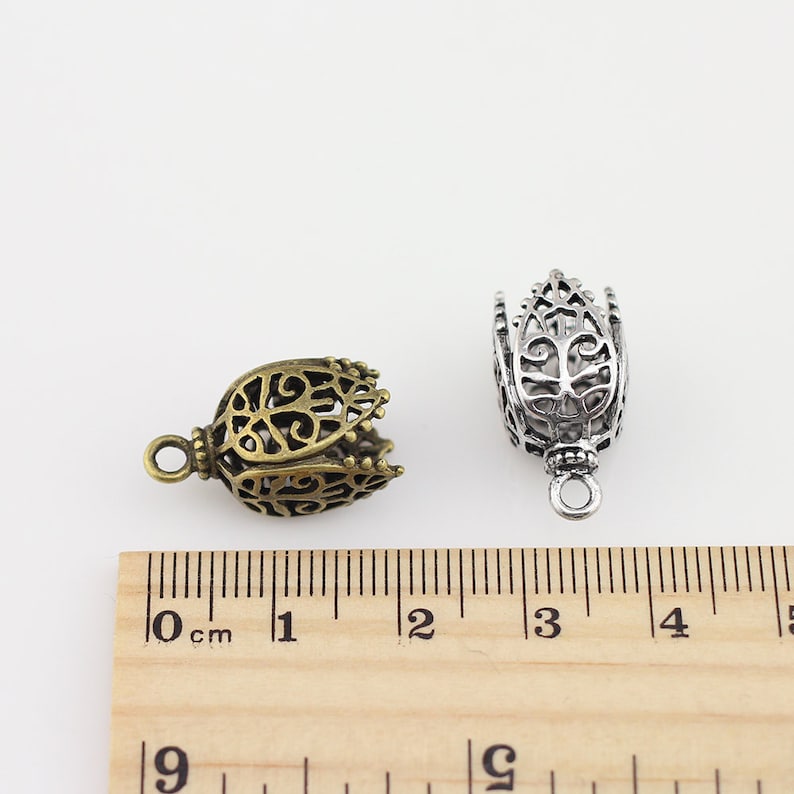 May include: Two metal filigree end caps for jewelry making. One is silver and one is bronze. The caps are about 1 inch long and have a delicate floral design.