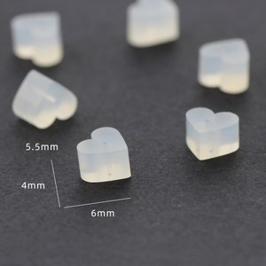 May include: Six clear heart-shaped silicone earring backs. The backs are 5.5 mm wide, 4 mm high, and 6 mm long.
