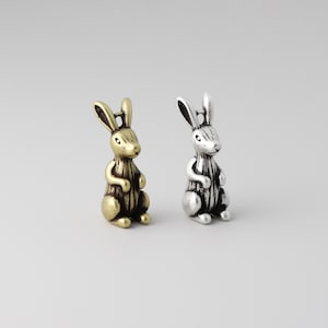 Peut inclure: Deux petites figurines de lapin en m&eacute;tal. L'une est dor&eacute;e, l'autre argent&eacute;e. Les deux lapins sont debout, les oreilles dress&eacute;es. Les figurines pr&eacute;sentent des d&eacute;tails et une esth&eacute;tique vintage. Ce sont probablement des objets d&eacute;coratifs ou des breloques.