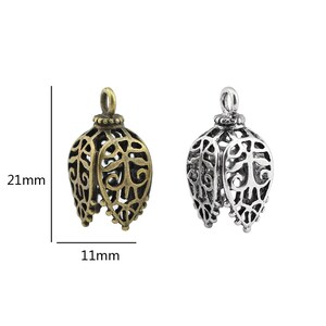 May include: Two ornate metal pendant charms, one in antique gold and one in silver, with a filigree design. Each charm measures 21 mm in height and 11 mm in width.