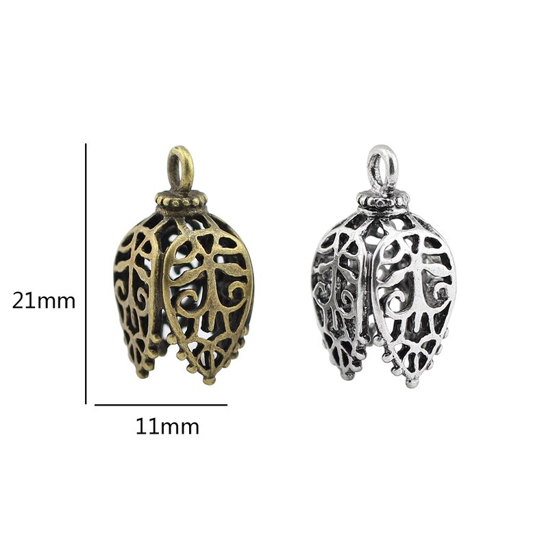 May include: Two ornate metal pendant charms, one in antique gold and one in silver, with a filigree design. Each charm measures 21 mm in height and 11 mm in width.