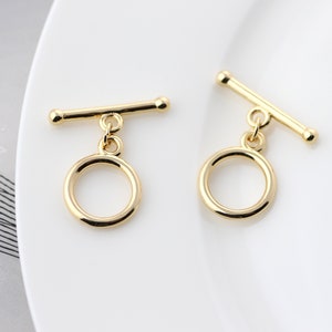 Può includere: Due chiusure a scorrimento in metallo dorato con un anello rotondo attaccato a ciascuna. Le chiusure sono progettate per essere utilizzate come chiusura per collane, braccialetti o altri gioielli.