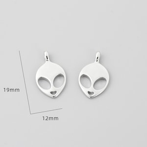 Op de afbeelding: Twee zilveren alien-hoofdcharms, elk 19 mm hoog en 12 mm breed.