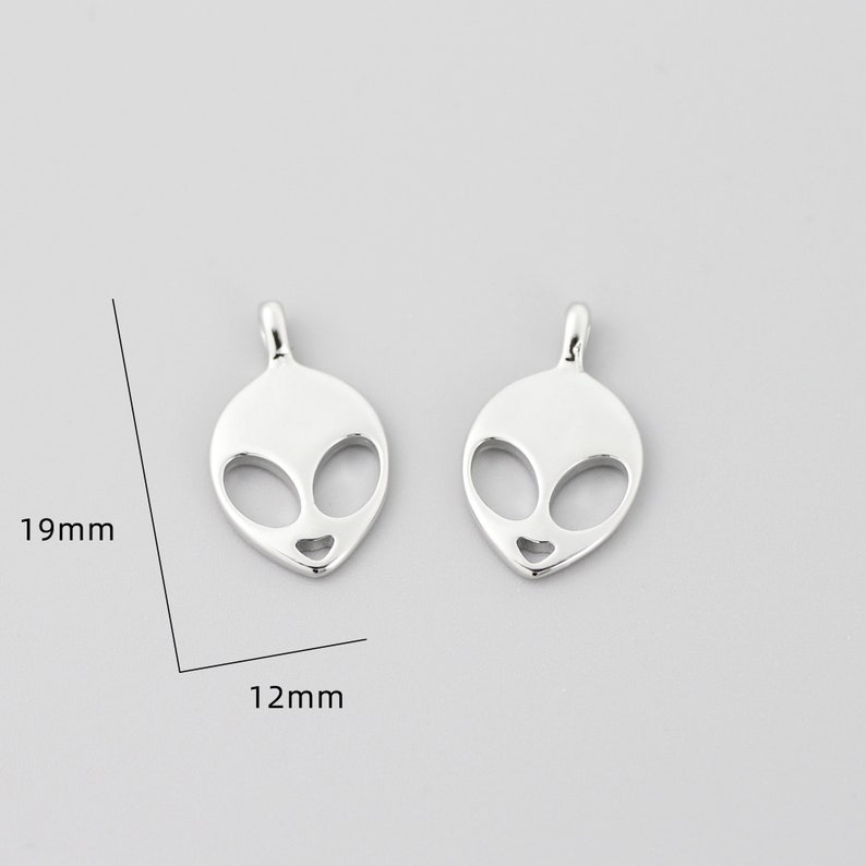 Op de afbeelding: Twee zilveren alien-hoofdcharms, elk 19 mm hoog en 12 mm breed.