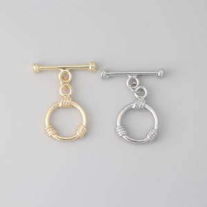 Può includere: Due chiusure a scatto, una dorata e una argentata, con un anello rotondo e attorcigliato. Le chiusure sono utilizzate per la creazione di gioielli.