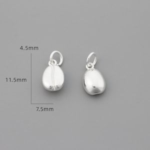 K&ouml;nnte beinhalten: Zwei silberne Kaffebohnen-Anh&auml;nger, jeder 11,5 mm lang, 7,5 mm breit und 4,5 mm hoch.