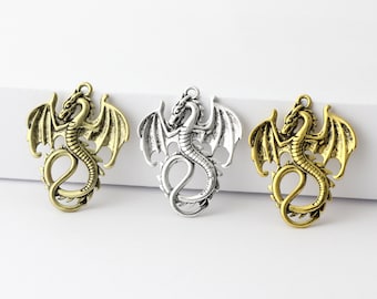 May include: Three silver dragon charms with open wings. The charms are in different finishes: gold, silver, and antique bronze.