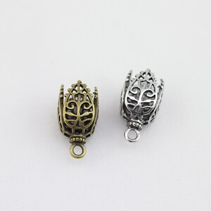 May include: Two ornate metal end caps for jewelry making. One is silver and the other is gold.