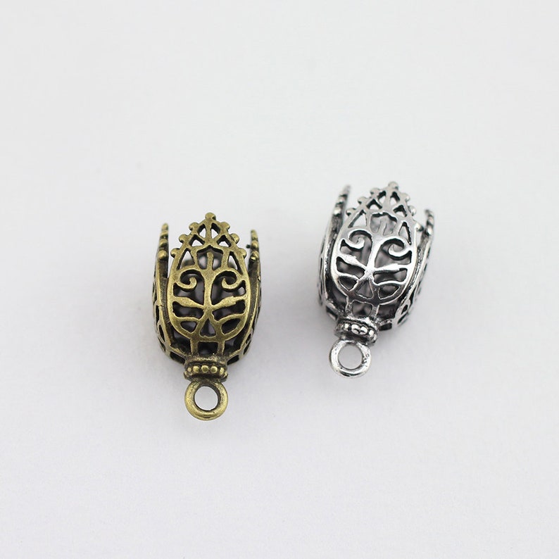 May include: Two ornate metal end caps for jewelry making. One is silver and the other is gold.