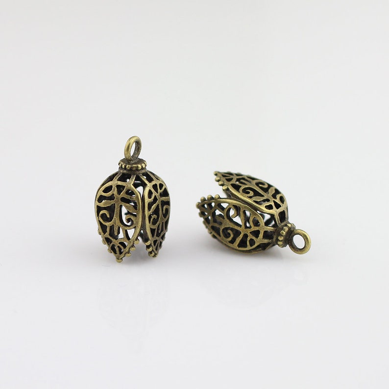 May include: Two antique gold filigree metal bell-shaped pendant caps with a decorative design.