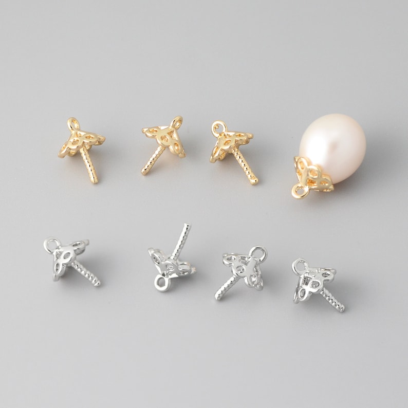May include: A set of gold and silver pearl cap findings. The findings are made of metal and have a delicate, intricate design. They are used to attach pearls to jewelry.