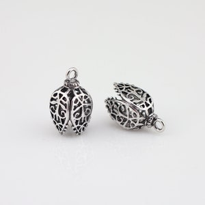 May include: Two silver filigree metal caps for jewelry making. The caps are open at the top and have a delicate, intricate design.