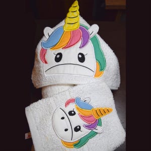 May include: White hooded towel with a rainbow unicorn embroidered on the hood and a smaller unicorn embroidered on the towel.