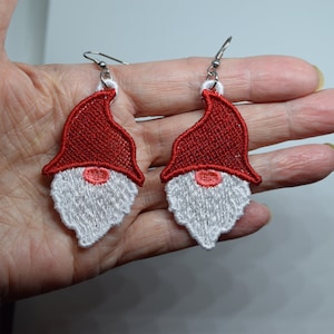 May include: A pair of red and white gnome earrings. The gnomes have white beards and red hats.