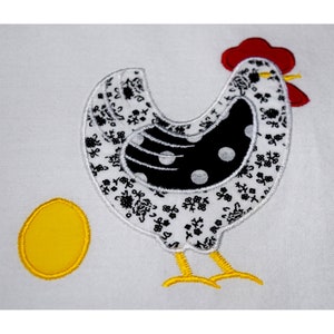 Peut inclure: Broderie représentant une poule blanche avec des pois noirs et blancs, une crête rouge et des pattes jaunes. La poule pond un œuf jaune.