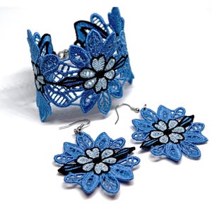 May include: A matching jewelry set featuring a blue lace bracelet and earrings. The bracelet is a wide band with a floral design, and the earrings are flower-shaped with silver hooks. The set is made of blue lace with black and light blue accents.