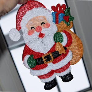 May include: Embroidered Santa Claus figure with a smiling face, red suit, and white beard. He carries a sack of gifts and wears a black belt with a gold buckle. The figure has green gloves and black boots, perfect for Christmas decorations.