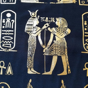 On the theme of Ancient Egypt fabric with golden pharaohs and hieroglyphs printed on dark blue fabric for cloth making. Sold by 50cm - 20 in