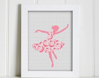 May include: A framed cross-stitch design of a pink ballerina with a floral skirt. The ballerina is in a dancing pose with her arms outstretched.