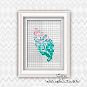 May include: A framed cross-stitch artwork with a geometric design in teal, pink, and white. The piece is in a white wooden frame, set against a white background. The text "Design by Modern Cross Stitch Art" is visible at the bottom of the frame.