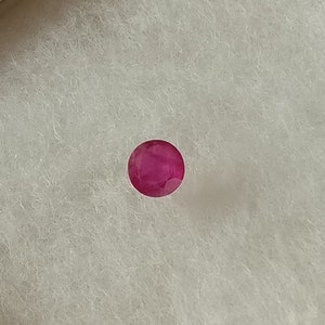 Puede incluir: Una piedra preciosa redonda de color rosa con una superficie lisa y pulida.