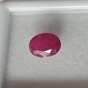 Könnte beinhalten: Ein lebhafter, ovaler Edelstein in Pink mit Facetten, auf weißem Hintergrund dargestellt.