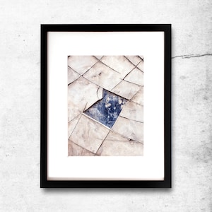 May include: A framed abstract photograph of a cracked and weathered surface with a blue patch in the centre.