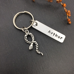 May include: Silver keyring with a snake charm and a personalised tag that reads "Arthur".