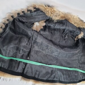 May include: Black fur vest with a brown fur collar. The vest is lined with a black fabric with a paisley pattern. A measuring tape is laid across the vest.