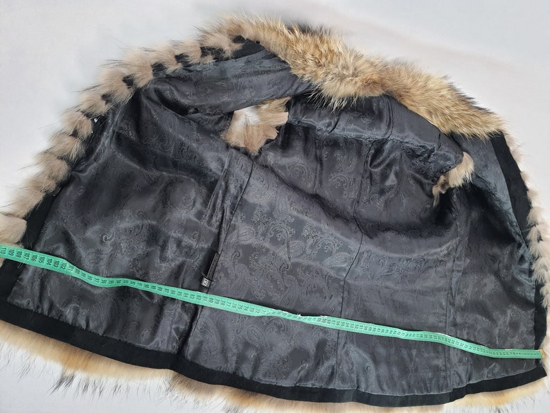 May include: Black fur vest with a brown fur collar. The vest is lined with a black fabric with a paisley pattern. A measuring tape is laid across the vest.