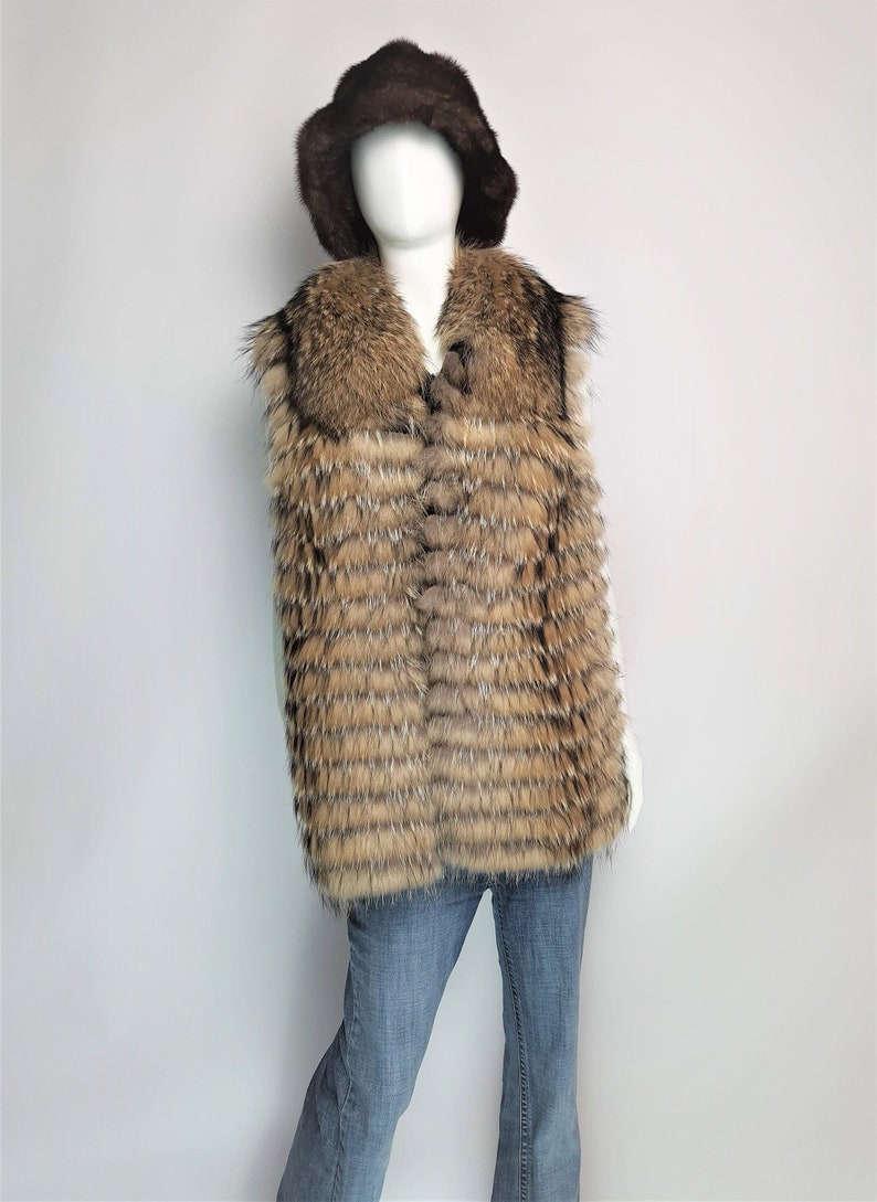 May include: A brown fur vest with a brown fur collar and a brown fur hat. The vest is sleeveless and has a button closure. The hat is a bucket style.