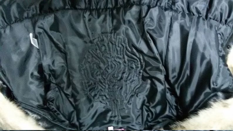 Pu&ograve; includere: Fodera nera trapuntata di un cappotto di pelliccia. La fodera &egrave; liscia e presenta un motivo trapuntato.