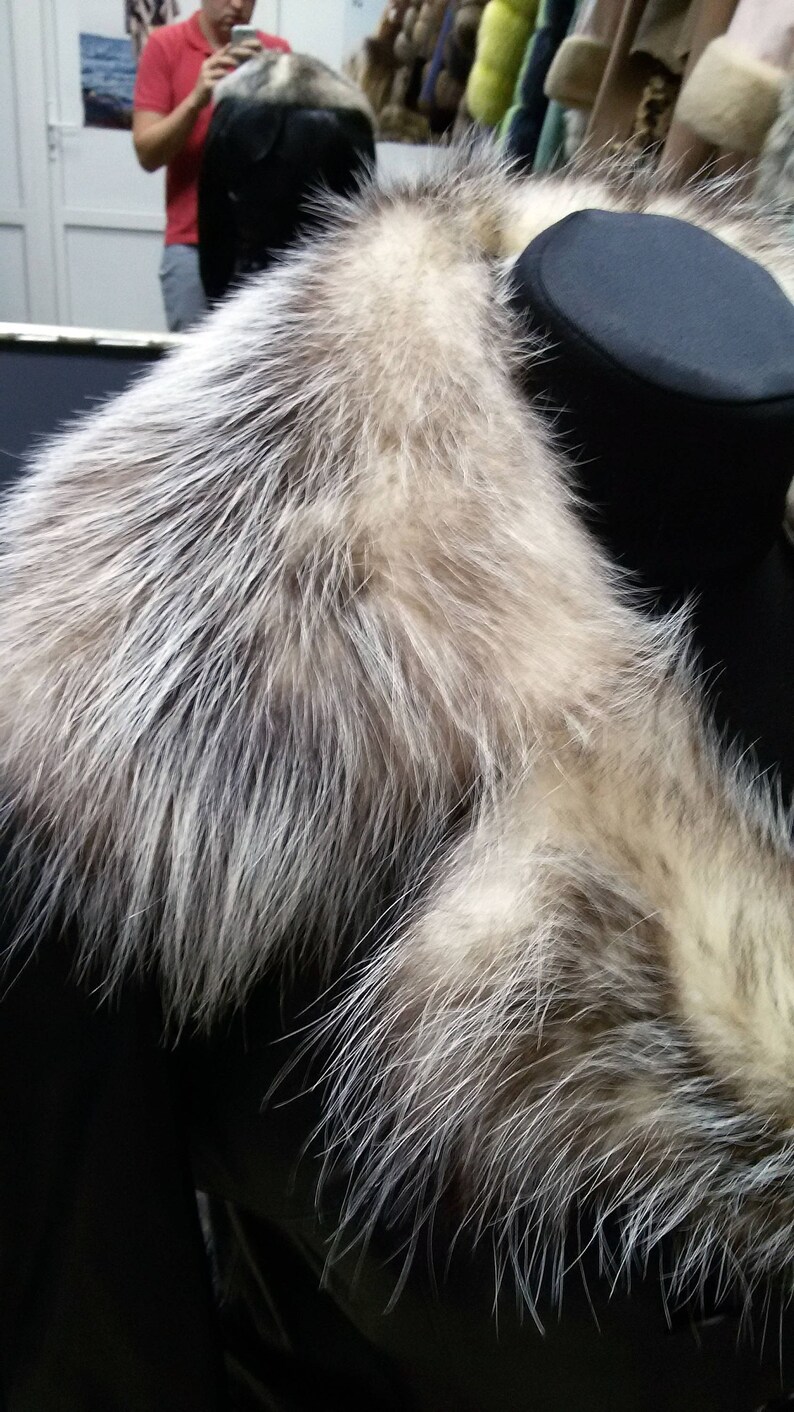 Pu&ograve; includere: Un colletto di pelliccia nero con bordino di pelliccia bianca. Il colletto &egrave; esposto su un manichino nero.